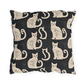 Cream folk art cats on a near-black outdoor pillow, worn block print