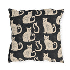 Cream folk art cats on a near-black outdoor pillow, worn block print