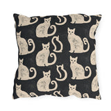Cream folk art cats on a near-black outdoor pillow, worn block print
