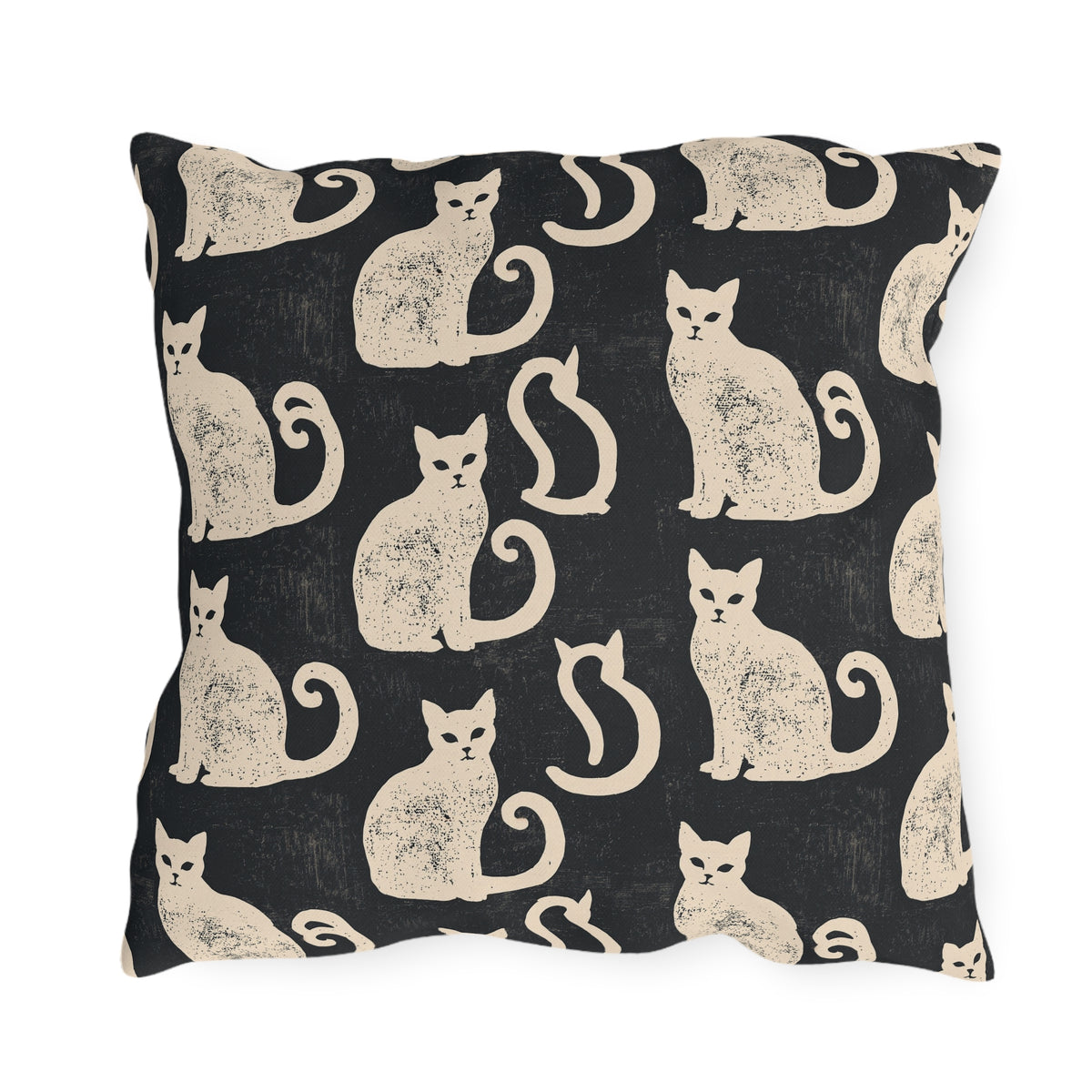 Cream folk art cats on a near-black outdoor pillow, worn block print