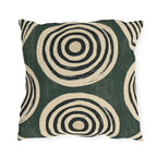 Black and cream concentric rings on a mottled forest green outdoor pillow