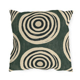 Black and cream concentric rings on a mottled forest green outdoor pillow