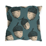 Oversized cream and black block print acorns on a deep teal outdoor pillow