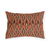 Nested ikat diamonds in charcoal and cream on a burnt rust outdoor lumbar pillow
