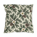 White winter roses, cedar, pinecones and white berries on a cream outdoor pillow