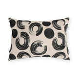 Black brush rings and solid dots on an oatmeal outdoor lumbar pillow