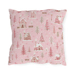 Snow-covered pink cottages and fir trees on pink outdoor pillow