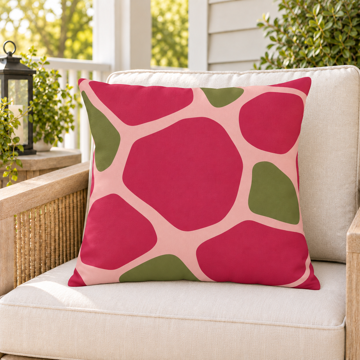Pink and olive pebble outdoor pillow styled on patio furniture