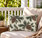 Cream outdoor lumbar pillow with pinecones and evergreen branches, second view