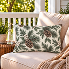 Cream outdoor lumbar pillow with winter greenery and pinecones, second view