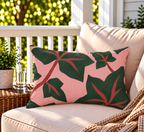 Pink and green ivy leaf outdoor lumbar pillow styled on patio furniture
