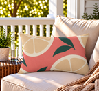 Coral citrus slice outdoor lumbar pillow styled on patio furniture