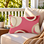Pink and red modern circle outdoor lumbar pillow styled on patio furniture