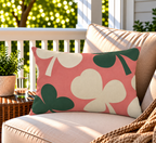 Coral clover leaf outdoor lumbar pillow styled on patio furniture