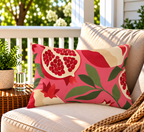 Pink and red pomegranate outdoor lumbar pillow styled on patio furniture