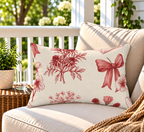 Red toile love letter floral outdoor lumbar pillow styled on patio furniture