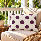 Aubergine polka dot outdoor lumbar pillow styled on patio furniture