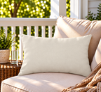 Solid cream neutral outdoor lumbar pillow styled on patio furniture