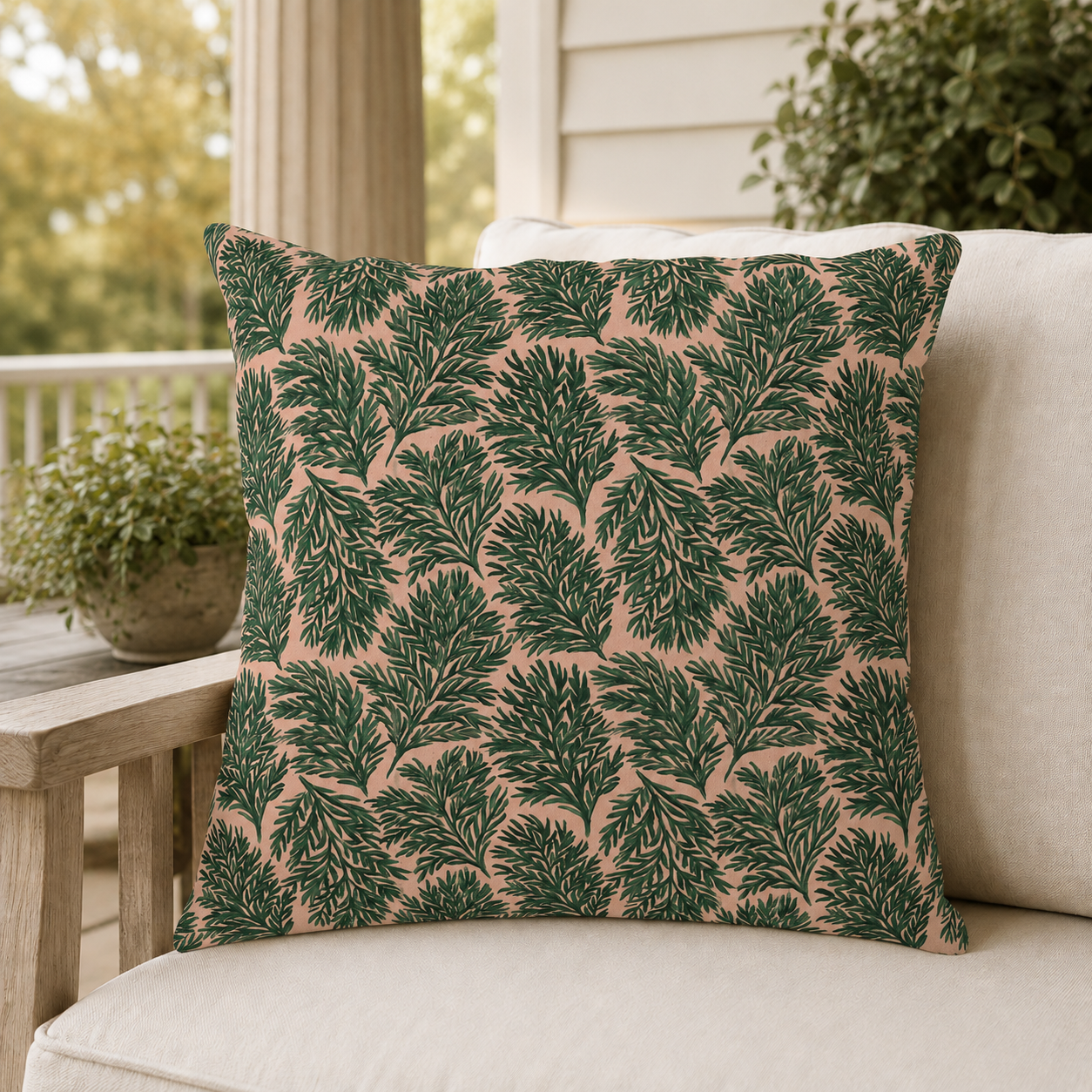 Dark green pine sprigs on blush peach outdoor pillow