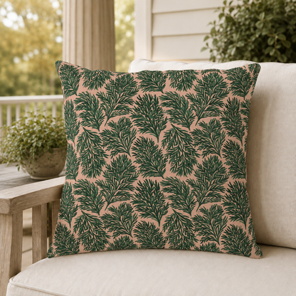 Dark green pine sprigs on blush peach outdoor pillow