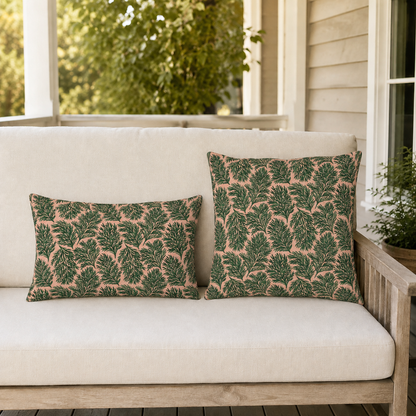 Dark green pine sprigs on blush peach outdoor pillow