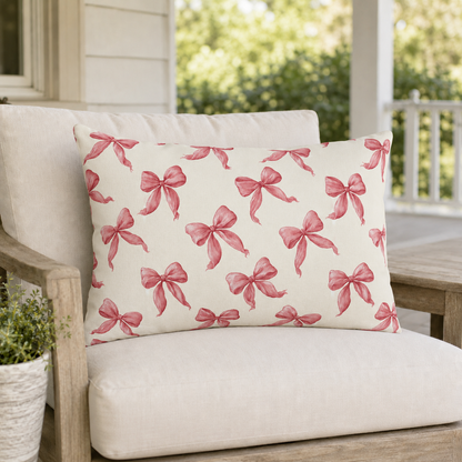 Rose pink engraved ribbon bows scattered on cream outdoor lumbar pillow