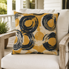 Mustard yellow outdoor pillow with navy brushed circles on a porch chair