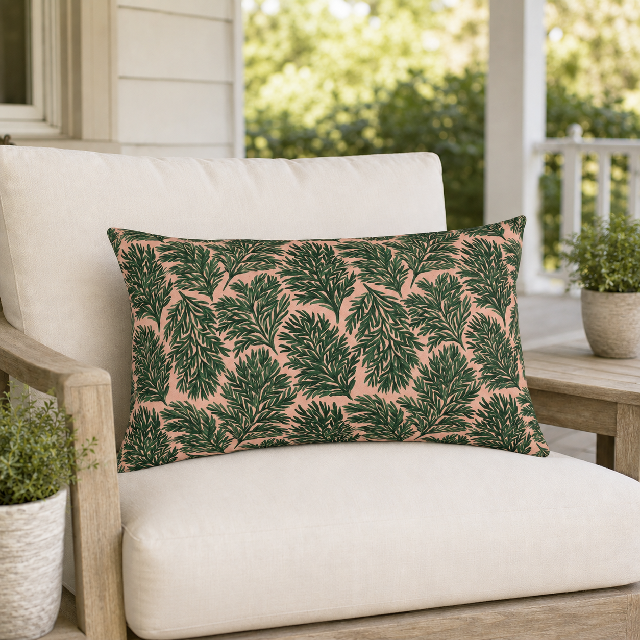 Dark green pine sprigs on blush peach outdoor lumbar pillow