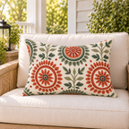Terracotta and sage folk medallion outdoor lumbar pillow styled on patio furniture