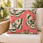 Coral pink moth outdoor pillow styled on patio furniture