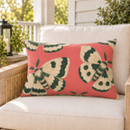 Coral pink moth outdoor lumbar pillow styled on patio furniture