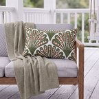 Green and red dotted fan outdoor lumbar pillow styled on patio furniture