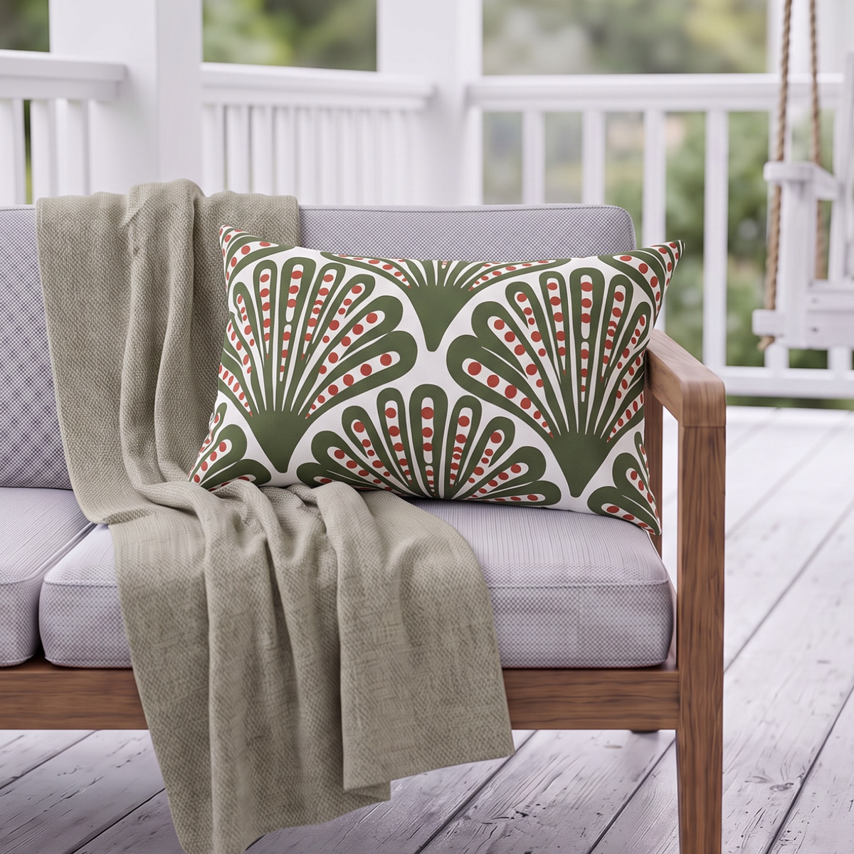 Green and red dotted fan outdoor lumbar pillow styled on patio furniture