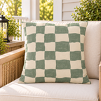 Sage green painted checkerboard outdoor pillow styled on patio furniture