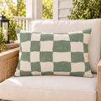 Sage green painted checkerboard outdoor lumbar pillow styled on patio furniture