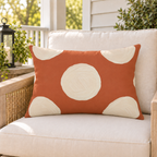 Terracotta and cream polka dot outdoor lumbar pillow styled on patio furniture