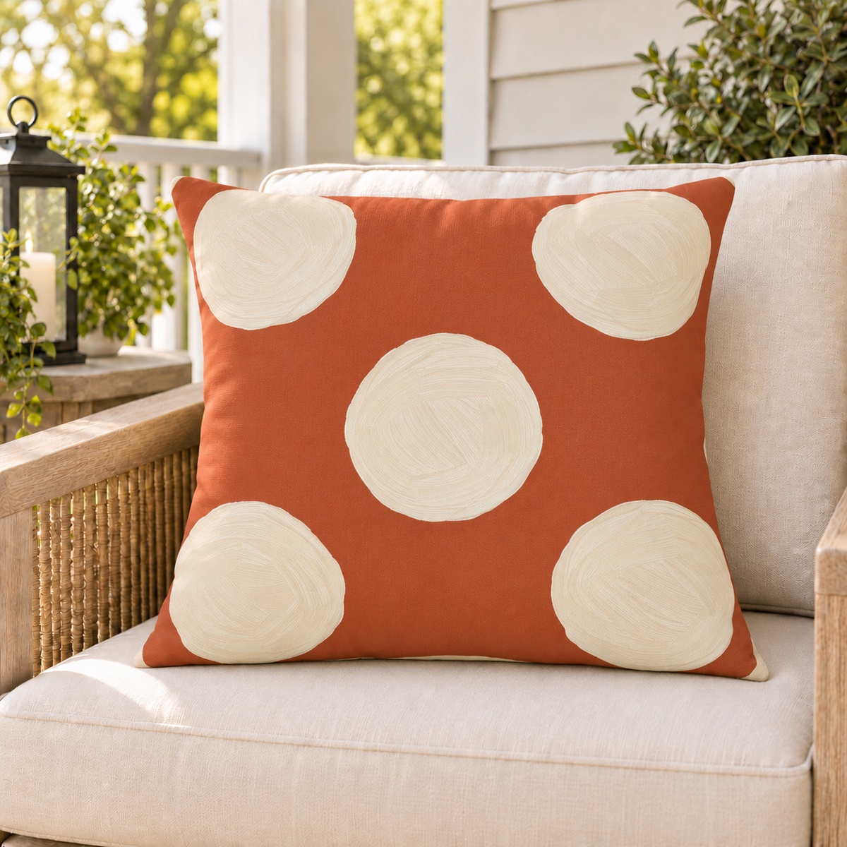 Terracotta and cream polka dot outdoor pillow styled on patio furniture