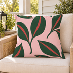 Pink and green leaf outdoor pillow styled on patio furniture