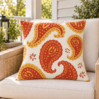 Rust and mustard paisley outdoor pillow styled on patio furniture