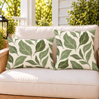 Sage green abstract leaf outdoor pillow and outdoor lumbar pillow styled together as a set on a porch loveseat