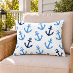 Light blue anchor outdoor lumbar pillow on a rattan chair on a sunny summer porch
