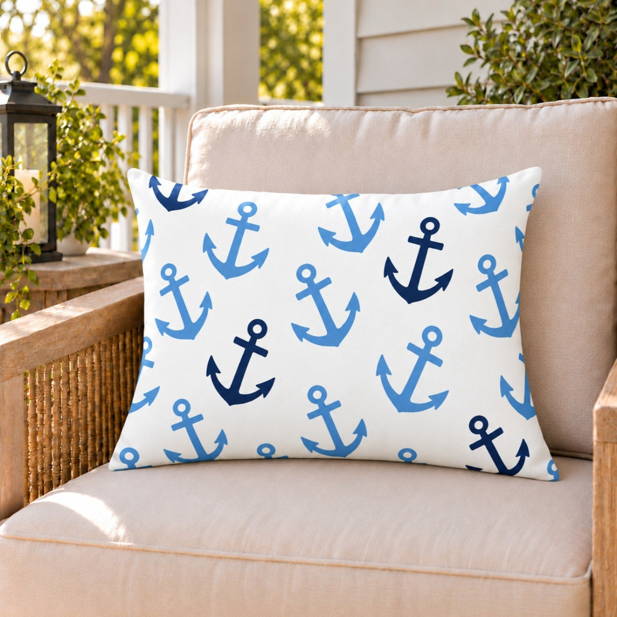 Light blue anchor outdoor lumbar pillow on a rattan chair on a sunny summer porch