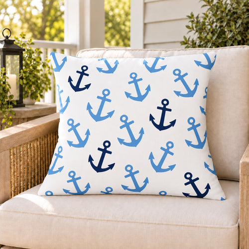 Light blue anchor outdoor pillow on a rattan chair on a sunny summer porch