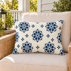 Navy block print medallion outdoor lumbar pillow on a rattan chair on a sunny summer porch