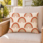 Boho rainbow arch outdoor lumbar pillow on a rattan chair on a sunny summer porch