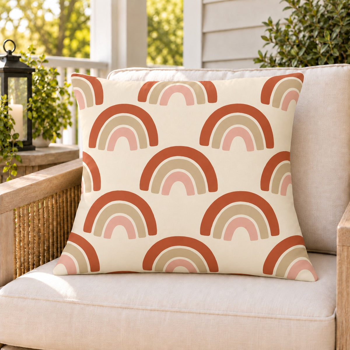 Boho rainbow arch outdoor pillow on a rattan chair on a sunny summer porch