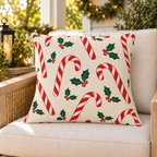 Red candy cane Christmas outdoor pillow on a rattan chair on a cozy holiday porch decorated with greenery and lights