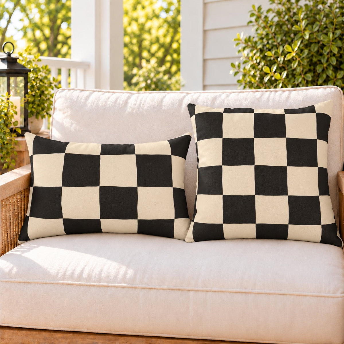 Black and cream checkerboard outdoor pillow and outdoor lumbar pillow styled together as a set on a porch loveseat
