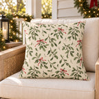 Green Christmas mistletoe outdoor pillow on a rattan porch chair with Christmas garland and warm lights