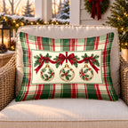 Green plaid ornament outdoor lumbar pillow on a rattan chair on a snowy Christmas porch